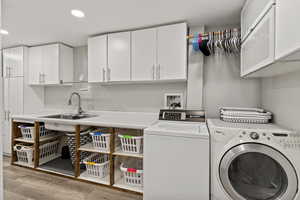Laundry area with washer and clothes dryer, recessed lighting, light wood-style flooring, and cabinet space
