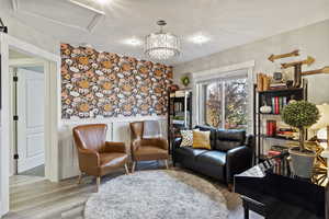 Living area featuring a wainscoted wall, wood finished floors, wallpapered walls, and a chandelier