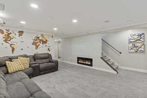 Carpeted living room featuring a glass covered fireplace, recessed lighting, stairs, and ornamental molding