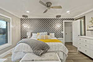 Bedroom featuring wood finished floors, wallpapered walls, an accent wall, ceiling fan, and recessed lighting