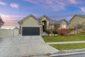 View of front of home with a gate, stucco siding, concrete driveway, and brick siding