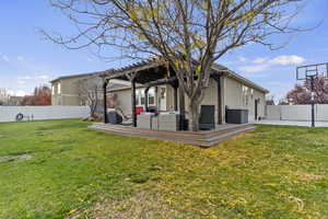 Rear view of property with a fenced backyard, stucco siding, a wooden deck, and a pergola