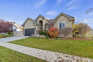Ranch-style house with stucco siding, brick siding, concrete driveway, and an attached garage