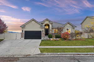 Ranch-style home featuring a gate, concrete driveway, stucco siding, brick siding, and a garage