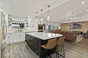 Kitchen with white cabinets, open shelves, a breakfast bar, decorative light fixtures, and appliances with stainless steel finishes