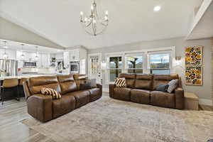 Living room with recessed lighting, light wood-style flooring, lofted ceiling, and a chandelier