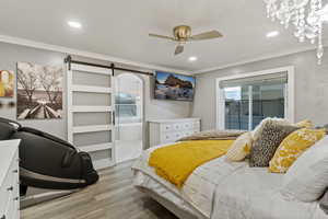 Bedroom featuring a barn door, light wood-style floors, access to outside, multiple windows, and recessed lighting