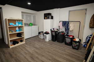 Washroom with wood finished floors, washing machine and dryer, and recessed lighting