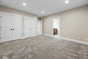 Unfurnished bedroom featuring multiple closets, carpet floors, recessed lighting, and ensuite bath