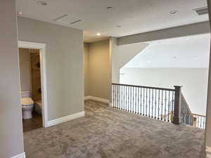 Hallway with carpet, a textured ceiling, tile patterned flooring, and recessed lighting