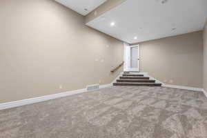 Below grade area with recessed lighting, light colored carpet, and stairs