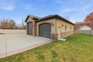 View of side of home with stucco siding, an attached garage, driveway, and brick siding