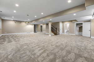 Finished below grade area featuring stairway, light carpet, recessed lighting, and track lighting