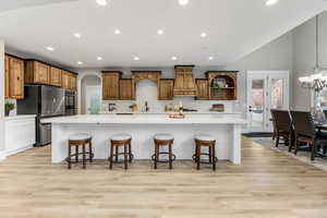 Kitchen with a large island with sink, arched walkways, a kitchen bar, freestanding refrigerator, and recessed lighting