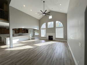 Unfurnished living room with high vaulted ceiling, light wood-type flooring, a glass covered fireplace, a ceiling fan, and recessed lighting