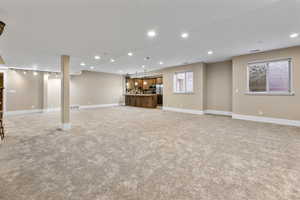Unfurnished living room featuring recessed lighting, light carpet, and bar