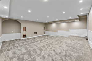 Basement with recessed lighting, arched walkways, and light colored carpet
