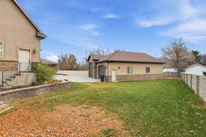 View of side of property featuring a fenced backyard, stucco siding, driveway, brick siding, and an attached garage