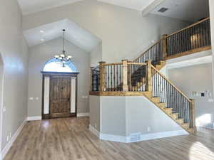 Foyer featuring high vaulted ceiling, wood finished floors, a chandelier, recessed lighting, and stairway