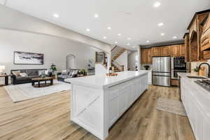 Kitchen with open floor plan, arched walkways, stainless steel appliances, light wood-type flooring, and recessed lighting