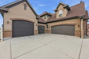 View of front of property featuring concrete driveway, stucco siding, and brick siding