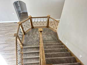 Stairs featuring arched walkways and wood finished floors