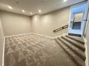 Finished below grade area with recessed lighting, carpet flooring, and stairs