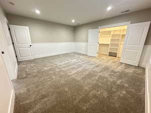 Unfurnished bedroom featuring a walk in closet, carpet flooring, recessed lighting, and wainscoting