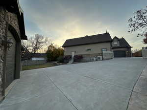 View of property exterior featuring stucco siding, a garage, a patio, stone siding, and concrete driveway