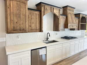 Kitchen featuring backsplash, light stone counters, appliances with stainless steel finishes, and a textured ceiling
