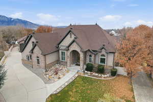 French country home with a gate, stone siding, roof with shingles, stucco siding, and concrete driveway