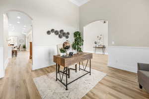 Office space featuring arched walkways, light wood-style floors, and recessed lighting