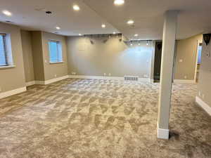 Basement with light carpet, recessed lighting, and rail lighting
