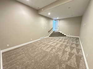 Carpeted empty room featuring recessed lighting and stairs