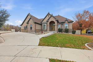 French provincial home featuring stucco siding and stone siding