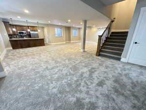 Unfurnished living room with recessed lighting, stairway, and carpet floors