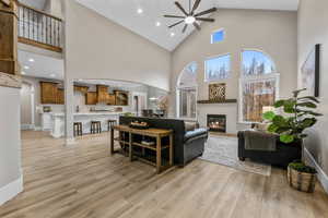 Living room with arched walkways, high vaulted ceiling, recessed lighting, ceiling fan, and a glass covered fireplace