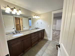 Full bathroom featuring a textured ceiling, double vanity, and a tile shower
