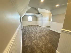 Additional living space with carpet floors, vaulted ceiling, a ceiling fan, and a textured ceiling