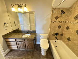 Bathroom featuring vanity, shower / washtub combination, and dark tile patterned flooring