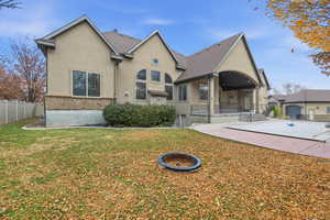 Back of property with stucco siding, a patio, a fire pit, and brick siding