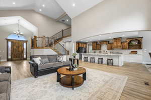 Living room featuring a chandelier, light wood-style floors, arched walkways, recessed lighting, and stairway