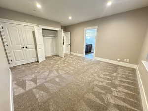 Unfurnished bedroom with light colored carpet, multiple closets, and recessed lighting