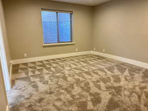 Empty room with light colored carpet and baseboards