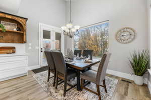 Dining space with a chandelier, a towering ceiling, and light wood finished floors