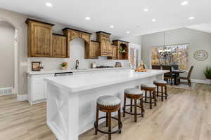 Kitchen with a spacious island, a breakfast bar, hanging light fixtures, recessed lighting, and light wood-style flooring
