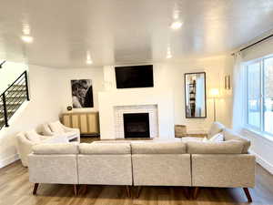 Living room featuring a fireplace, wood finished floors, stairway, and recessed lighting