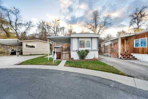 Manufactured / mobile home with concrete driveway, a carport, and a front lawn