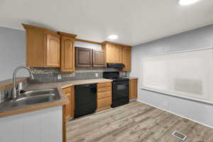 Kitchen featuring backsplash, black appliances, light wood-style floors, brown cabinetry, and recessed lighting