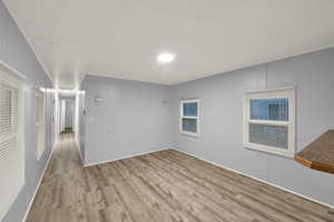 Empty room with light wood finished floors and a textured ceiling